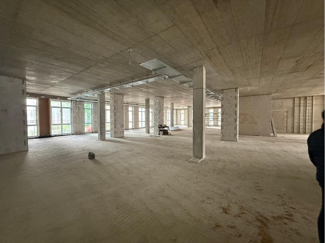 Blick in eine Etage des Rohbaus mit Betonstützen und großen Fensterfronten